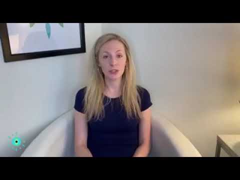 Person sitting in a chair speaking, framed by a light-colored wall and artwork, in a cozy, well-lit room setting.