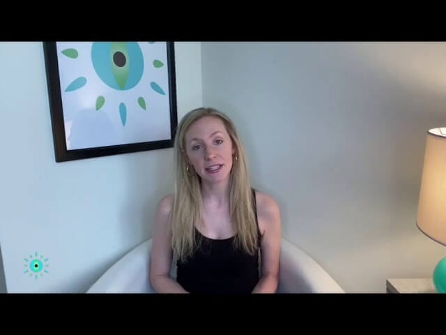 Woman sitting in a modern chair, minimalist room, abstract wall art, and lamp; peaceful home interior setting.